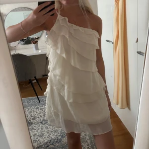 Vit omlottklänning med volanger - Säljer en jätte söt vit kortklänning med volanger och oneshoulder-design. storlek S❤️❤️