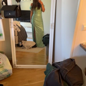 Mintgrön glittrig långklänning - Säljer min balklänning, en mintgrön långklänning med glittriga paljetter och offshoulder-design. Klänningen har en snygg slits framtill och figurnära passform som framhäver siluetten. Endast andvänd en kväll🩷 köptes för 1700-1900 nånstan med frakt💕storlek är som en xs-s💕ast lite smutsig nertill själva släppet på klänningen då det släpats på marken men bara synligt på insidan💕