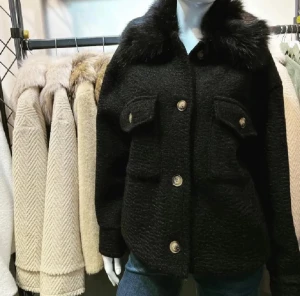 Svart teddykappa med fuskpäls - Säljer en svart teddykappa med fluffig fuskpäls på kragen och stora guldfärgade knappar framtill. Jackan har två rejäla fickor med lock och en loose passform som ger en chill vibe. Perfekt för dig som vill ha en mysig och snygg jacka till hösten och vintern.