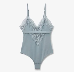 Ljusblå spetsbody med smala axelband - Helt ny!Supersnygg ljusblå body med spetsdetaljer framtill och baktill, samt smala justerbara axelband. Bodyn har v-ringad urringning och spets längs kanterna för en extra feminin vibe. Perfekt att styla med jeans eller kjol för en trendig look.