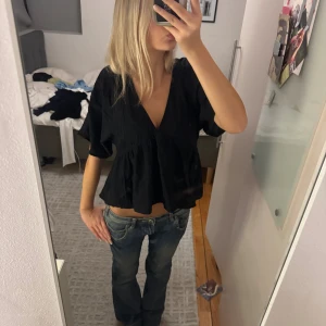 Svart blus med v-ringning - Säljer en svart blus med djup v-ringning och korta, lite vidare ärmar.