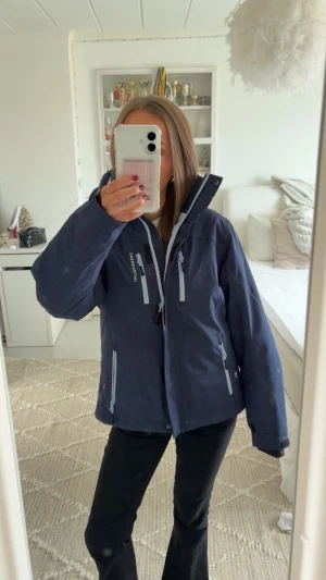 Mörkblå skidjacka från Swedemount  - Säljer en mörkblå skidjacka från Swedemount med ljusblå dragkedjor och hög krage. Jackan har flera praktiska fickor med dragkedja och en loose passform. Perfekt för dig som gillar att åka skidor och vill ha en snygg och funktionell jacka. Storlek 164, använd en gång😊