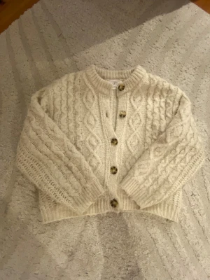 Beige stickad kofta från Zara - Supermysig beige stickad kofta från Zara med stora bruna knappar💓jätte fin och är i ett bra skick! Köptes för 450kr i våras så är inte jätte gammal! Storlek 146/152 men skulle säga passar XXS och även kanske en liten XS! Jätte skön att ha på sig och värmer bra!