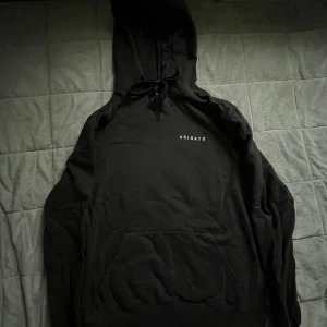 Svart hoodie från Axel Arigato - Svart hoodie från Axel Arigato med minimalistisk vit logga på bröstet. Klassisk känguruficka, snörning i huvan och mjukt material. En hoodie som funkar året runt. Den har ett slit vid halsen men så därför säljs den billigt. Skriv pris förslag vid intresse.