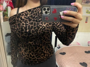 Ginas leopardmönstrad offshoulder topp - Säljer en snygg asymmetrisk offshoulder topp från Gina Tricot i leopardmönster. Toppen är i tunn mesh med långa ärmar och har en brun bas med svarta fläckar. Materialet är återvunnen polyester och modellen är figurnära och trendig :)
