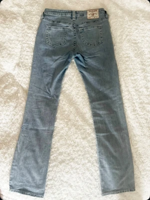 True Religion ljusblå jeans straight fit - Säljer ett par SÅ snygga jeans från True religon. Modell ”Billie midrise straight” vilket alltså är en modell med medelhög/låg midja och rak/lite smått utsvängda i benen. Långa i benen!! Marginal på mig som är 170! Stretchiga och så sköna. Säljer för att de tyvärr har blivit för små för mig😊. Jättebra skick, inga defekter alls. Nypris 1300kr Storlek W27 