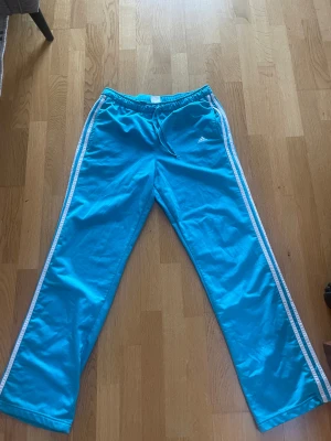 blå adidasbyxor  - blå baggy adidasbyxor, står ingen exakt storlek men skulle gissa på M, långa på mig som är 168. köpta i danmark.