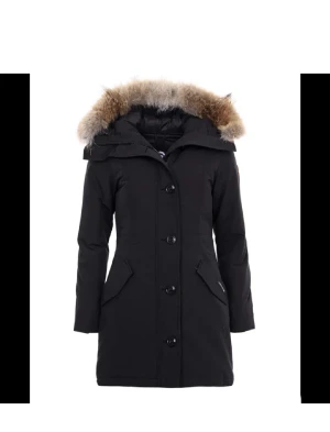 Canada Goose Rossclair Parka - Säljer en svart lång dunjacka från Canada Goose med huva och klassisk logga på ärmen. Jackan har stora fickor framtill, diskret Canada Goose-märke och stängs med både dragkedja och knappar. Perfekt för kalla dagar och riktigt snygg passform.