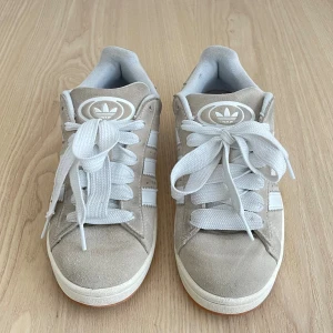 Adidas Campus 00’s beige - Säljer mina Adidas Campus 00’s i beige. De är väl använda och har en del fläckar och märken, men fina och bekväma oavsett. Kan mötas upp i Sthlm, annars står köparen för frakten 🩷