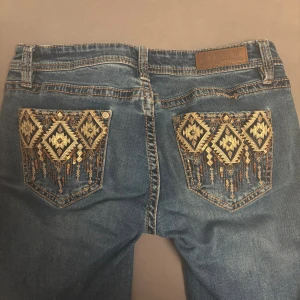 Lowwaist jeans med coola fickor - Blå jeans från Rock & Roll med snygga bakfickor med paljettdetaljer. Jätte bra kvalité.