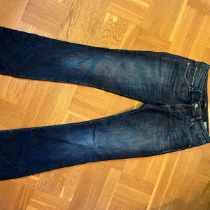 Mavi Bella Mid-Rise Bootcut Jeans - Mörkblå jeans från Mavi, modell Bella Mid-Rise med slim bootcut passform. Storlek 28/34. Lite slitningar längst ner
