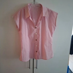Söt randig blus - Söt egensydd ärmlös skjorta med rosa och vita ränder, spetsdetaljer vid ärmöppningarna och söta knappar. 