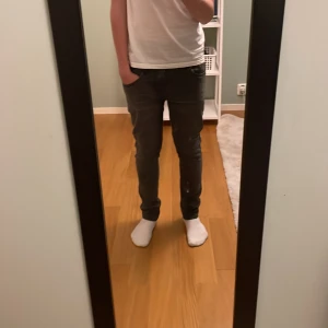 Levis 512 jeans - Säljer ett par mörkgrå skinny jeans med klassisk femficksdesign. Jeansen har en smal passform och är tillverkade i stretchigt material för extra komfort. Perfekta för dig som gillar en tajt look och vill ha ett par stilrena jeans i garderoben.
