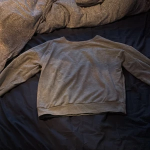 Grå sweatshirt från ONLY - Enkel och stilren grå sweatshirt från ONLY i storlek S. Tröjan har rund halsringning, långa ärmar och ribbade muddar vid ärmslut och nederkant. Perfekt för en chill och avslappnad look.