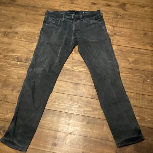 Replay Anbass Hyperflex svarta jeans - Svarta Replay Anbass Hyperflex jeans med klassisk femficksdesign och smal passform. Jeansen är tillverkade i stretchigt material för extra komfort och har diskreta slitningar för en cool look. Perfekta för dig som gillar stilrena och bekväma jeans.