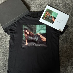 Svart Limited Edition t-shirt Limitato - Exklusiv svart t-shirt från Limitato med konstmotiv av Terry O’Neill tryckt på bröstet. Gjord i merceriserad bomull för en lyxig känsla. Kommer i originalbox och med äkthetsintyg, endast 1500 exemplar. Hör av dig vid fler frågor eller funderingar!