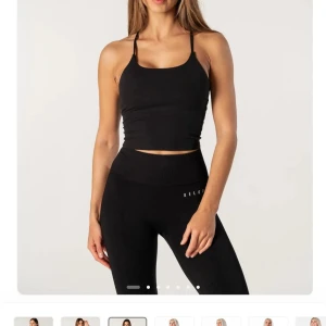 Svart croppad linnetopp Reload - Säljer en svart croppad linnetopp från Reload med tunna axelband och tight passform. Toppen har en stilren design med rundad halsringning och smala band i ryggen. Perfekt för träning eller när du vill ha en sportig look.