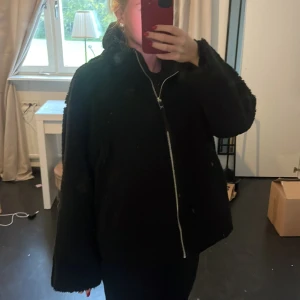 Teddyjacka - Mysig svart teddyjacka från Amisu med hög krage och hel dragkedja framtill. Jackan har en oversized passform och är tillverkad i fluffigt syntetmaterial. Passar som en S💗