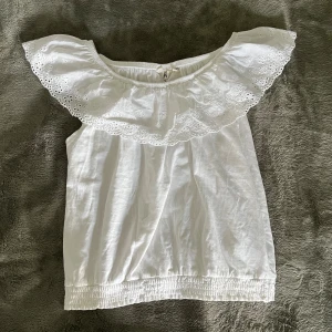 Vit offshoulder topp från KappAhl - Superfin vit offshoulder topp från KappAhl med bred volangkant och broderade blommor längs axlarna. Storleken är 134/140 men skulle säga att den passar även xxs/xs. Skriv vid fler frågor!💓