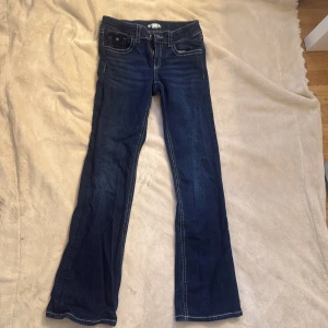 Mörkblå bootcut jeans Gina Tricot - Mörkblå jeans från Gina Tricot i storlek 164. Klassisk bootcut-modell med kontrastsömmar, fem fickor och snygga detaljer på bakfickorna. Jeansen har normal passform och är tillverkade i mjukt denimtyg. Använda cirka 3 gånger så dom är inte slitna 