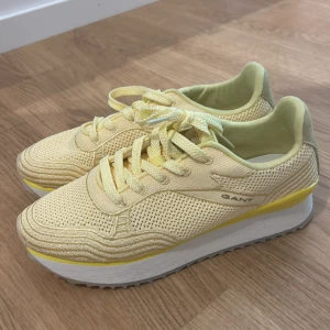 Gula sneakers från Gant med platåsula - Snygga sneakers från Gant i ljusgul mesh och textil med vita och gula detaljer. Skorna har snörning, rund tå och en rejäl vit platåsula med vågig undersida. Perfekta för dig som vill sticka ut med en fräsch färg och sportig vibe.