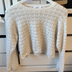 Vit stickad tröja från Zara - Superfin vit stickad tröja från Zara med snyggt hålmönster över hela tröjan. Den har rund halsringning och långa ärmar, perfekt för lager på lager under kyliga dagar. Enkel att matcha med jeans eller kjol.