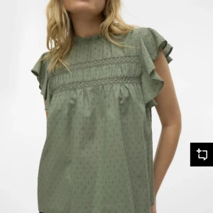 Grön blus med volangärmar - Säljer en ljusgrön blus med små diskreta prickar, volangärmar och fina spetsdetaljer över bröstet. Blusen har en lös passform och hög halsringning, perfekt för en avslappnad men ändå söt look.