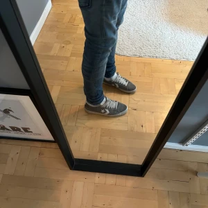 Grå Converse sneakers med vit detalj - Snygga grå Converse sneakers med vit stjärndetalj på sidan och vit sula. Skorna har snörning och är tillverkade i mocka med perforerad vit plös. Perfekta för dig som gillar klassisk streetstil.