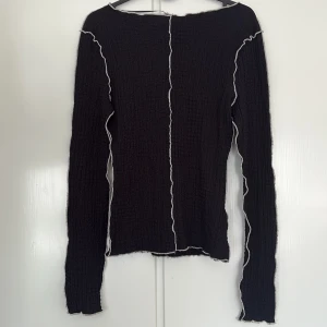 Svart långärmad topp från Lindex XS  - Svart långärmad topp från Lindex i storlek XS. Toppen har vågiga, synliga sömmar i vitt längs ärmar och framtill. Helt ny!