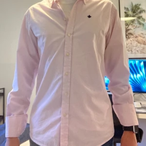 Morris skjorta rosa - Klassisk ljusrosa skjorta från Morris med button down-krage och broderad mörkblå logga på bröstet. Perfekt för en clean och stilren look. Köpt för 1350 kr så 449 som jag säljer den för är riktigt bra. Tveka inte att höra av dig vid frågor eller funderingar 😊. FRI FRAKT JUST NU!