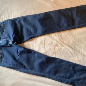 Blå Replay Anbass jeans - Säljer ett par mörkblå Replay Anbass jeans med klassisk femficksdesign och snygga kontrastsömmar. Jeansen har en rak passform och är tillverkade i mjukt jeansmaterial. Bakfickorna har coolt broderi och märkesdetaljer. Perfekta för dig som gillar stilrena grisch jeans!