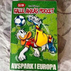 Kalle Ankas Pocket 519: Avspark i Europa - Följ Kalle Anka och hans vänner på fotbollsäventyr i Europa! Denna pocket är fylld med över 500 sidor serier, skratt, skoj och spännande matcher. Perfekt för dig som gillar humor, sport och roliga berättelser med Kalle i huvudrollen.
