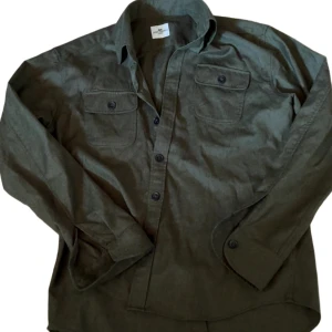 Olivgrön overshirt från John Henric - Olivgrön overshirt från John Henric med två bröstfickor och knappar framtill. Skjortan är i storlek M men kan passa S