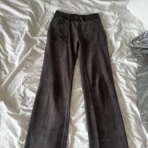 Grå mjukisbyxor Juicy Couture XXS - Säljer ett par grå mjukisbyxor från Juicy Couture i storlek XXS. Byxorna har bred resår med snörning i midjan, framfickor och bakfickor med knappar. Materialet är mjukt och skönt, perfekt för chill dagar. Stilen är loose med raka ben. Nästan aldrig använda eftersom jag inte gillade färgen på mig.💕