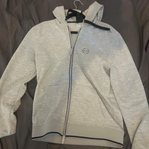 Grå hoodie från Armani Exchange - Snygg ljusgrå hoodie från Armani Exchange med dragkedja och huva. Storlek S
