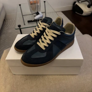 Maison Margiela Gats - Maison Margiela Gats sneakers i marinblått och mörkblått skinn och mocka, med beige snörning och klassisk gummisula. 