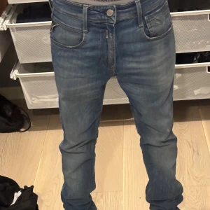 Replay jeans blå herr 28/34 - Säljer ett par snygga blå jeans från Replay i klassisk femficksmodell. Jeansen har raka ben, normal passform och coola slitningar på bakfickorna. Tillverkade i bomull med tydliga Replay-detaljer och logga på fickan. Perfekta för en avslappnad stil.