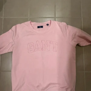 Rosa sweatshirt från GANT - Säljer en ljusrosa sweatshirt från GANT i storlek S. Tröjan har klassisk rund halsringning, broderad GANT-logga framtill och långa ärmar. Tillverkad i mjuk bomull som är skön att ha på sig. Perfekt för en chill och stilren look.