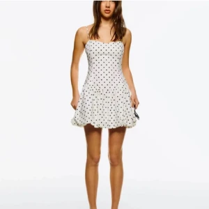 Vit prickig kort klänning - Supersöt vit kort klänning med svarta prickar och smala axelband. Använd en enda gång. Klänningen har en figurnära överdel och en lätt utställd kjol som ger en flowy känsla! Perfekt för fest💥