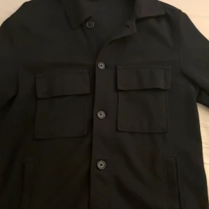 Overshirt - Stilren svart overshirt med klassisk krage och stora bröstfickor med lock. Perfekt nu mot hösten och lite kallare dagar, hör av er vid minsta intresse 