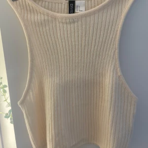 Beige, virkat ribbad linnetopp från H&M Divided - Säljer en beige ribbad linnetopp från H&M Divided i storlek M. Toppen är lite mindre i storleken och passar perfekt till en st S. Toppen är ärmlös med breda axelband och har en croppad passform. Perfekt för varma dagar och enkel att styla med jeans eller kjol.❤️😘