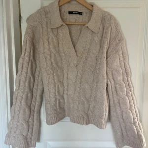 Beige kabelstickad tröja från Bik Bok - Säljer en beige kabelstickad tröja från Bik Bok i storlek XS.💛 Tröjan har en bred krage, v-ringning och långa ärmar. Den är grovstickad med snygga kabeldetaljer. Använd max tre gånger så i toppenskick💞