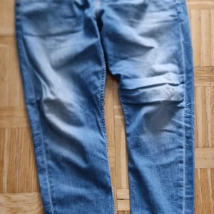 Ljusblå jeans från Calvin Klein 38/32 - Snygga ljusblå jeans från Calvin Klein med klassisk femficksdesign och diskret CK-logga på fickan. Jeansen har raka ben och normal passform, tillverkade i mjukt denimtyg som är skönt att bära hela dagen.