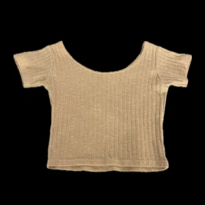 Rosa ribbad croppad topp - Säljer en rosa croppad topp med ribbad struktur och korta ärmar. Toppen har en bred, rundad urringning och är tillverkad i ett mjukt material som sitter snyggt på kroppen. Köpt i Thailand så vet inte vad det är för märke.