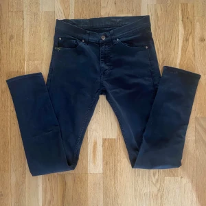 Svarta slim jeans från Tiger of Sweden - Snygga svarta jeans från Tiger of Sweden i modellen Straw. De har en slim passform, klassisk femficksdesign och raka ben. Jeansen är tillverkade i bomull med en skön stretch och passar perfekt till en clean och stilren look. Skick 9/10 använda fåtal gångerStorleken är 31/34