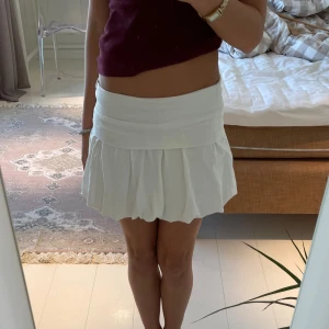 Vit mini balongkjol - Superfin vit kortkjol med bred midja och plisserad nederdel. Kjolen har en söt och ungdomlig vibe, perfekt för dig som gillar en fräsch och enkel stil. Passar snyggt till crop tops eller stickade tröjor. Lätt att matcha med sneakers eller boots.
