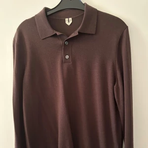 Stickad brun långärmad pikétröja Arket  - Säljer en stilren brun långärmad stickad pikétröja från Arket. Använd endast ett fåtal gånger och inga defekter. Skick 8/10. Nypris på denna är 699kr, mitt pris 250 kr. Skriv vid fundering. 