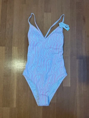 baddräkt med snörning - ny med prislapp - Säljer en snygg baddräkt från Cubus i ljusrosa och vitt med zebramönster. Baddräkten har smala axelband, v-ringad fram och cool snörning samt öppna partier i ryggen. Jättefin baddräkt i storlek S (36) Ny med prislapp på! Från Cubus - funkar vid alla tillfällen