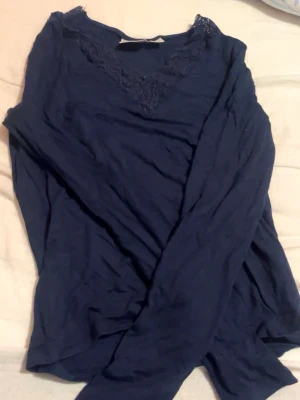 Mörkblå långärmad topp med spets - Säljer en mörkblå långärmad topp med snygg spetsdetalj vid v-ringningen. Toppen har en mjuk och skön känsla, perfekt för dig som gillar stilrena plagg med en liten twist. Passar till jeans eller kjol för en chill look. Från ginatricot storlek 146-152 🥰
