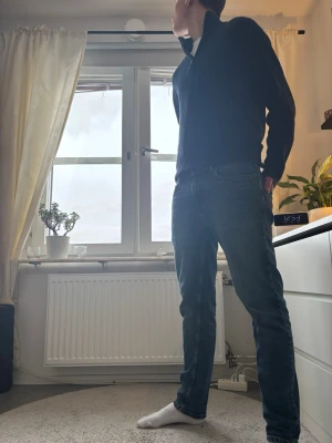 Mörkblå stickad half zip tröja - Säljer en mörkblå stickad tröja med half zip och hög krage. Tröjan har långärmade ärmar och en ribbad struktur som ger en snygg och stilren look. Perfekt för dig som gillar klassiska och enkla plagg med lite edge.
